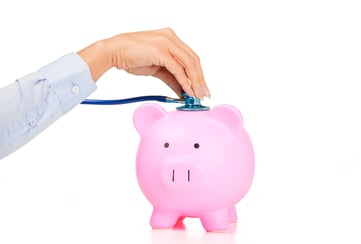 Woman hand stethoscope pink piggy bank. Financial system checkup | healthcare news | Primaris